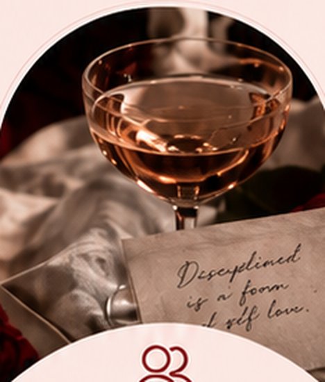 A coupe of rosé beside a handwritten note on cream silk, the words discipline is a form of self love